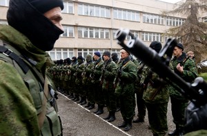 Armed man believed to be a Russian serviceman, stands near members of pro-Russian self defence unit before they take an oath to Crimea government in Simferopol
