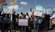 Photograph taken during a protest against the enforced demolition of community housing in Israel. The Arab-Bedouin community of Atir-Umm al-Hiran has been handed with house demolition orders, in order to facilitate the construction of a Jewish-only town, Hiran, in its place. The case has come to public attention after Israel’s Supreme Court rejected a petition against the removal of the residents in May 2015, arguing that the land belongs to the state and thus the Bedouin community has no legal right over Atir-Umm al-Hiran. The Supreme Court Justice recognised that the issue of Palestinian citizens of Israel’s housing rights is filled with “sensitive emotions and political disputes”, yet has failed to provide remedies to their residents. The village of Atir-Umm al-Hiran are two of 36 unrecognised Bedouin villages in Israel. In the district of Beersheba, where the village is located, only 1% of the villages have been formally recognised by the Israeli authorities. People take part in the demonstration including a man with a sign which reads - Stop House Demolition.